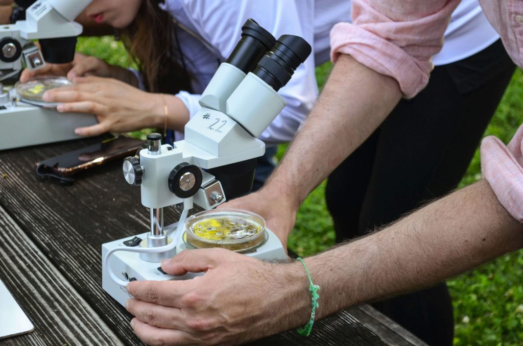 Biologiedocent kijkt samen met leerlingen onder de microscoop